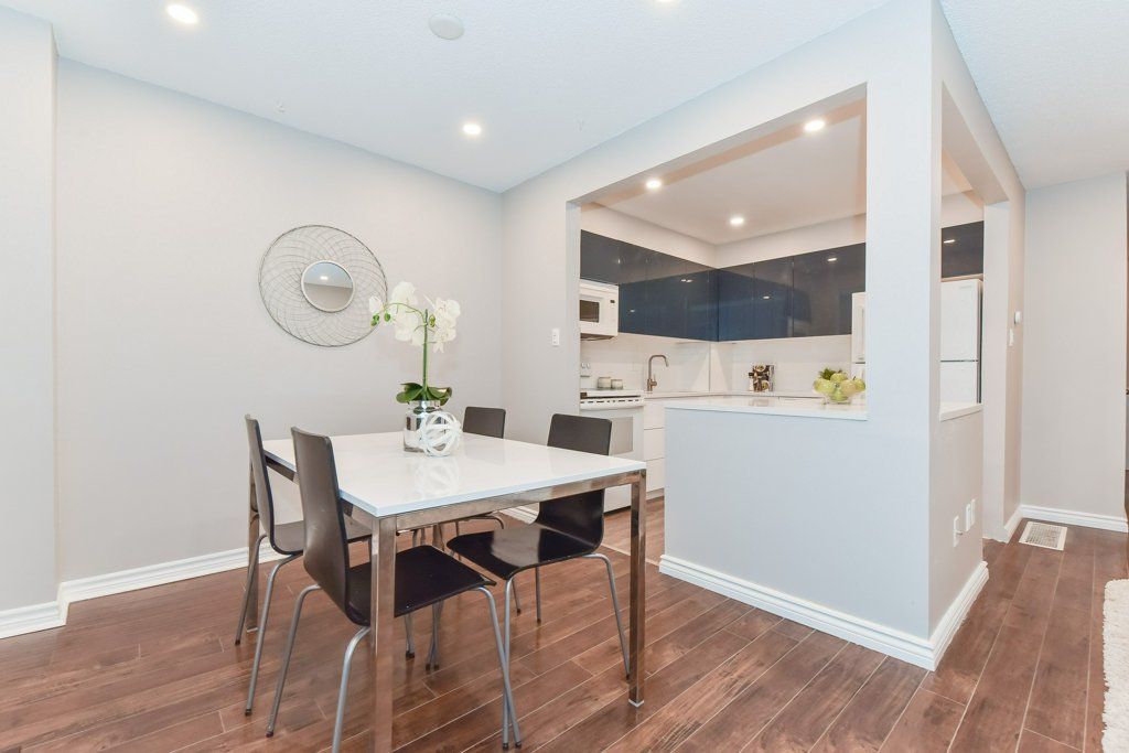 Dining room with a table, chairs, and a view into the kitchen. Dark wood floors, light walls.