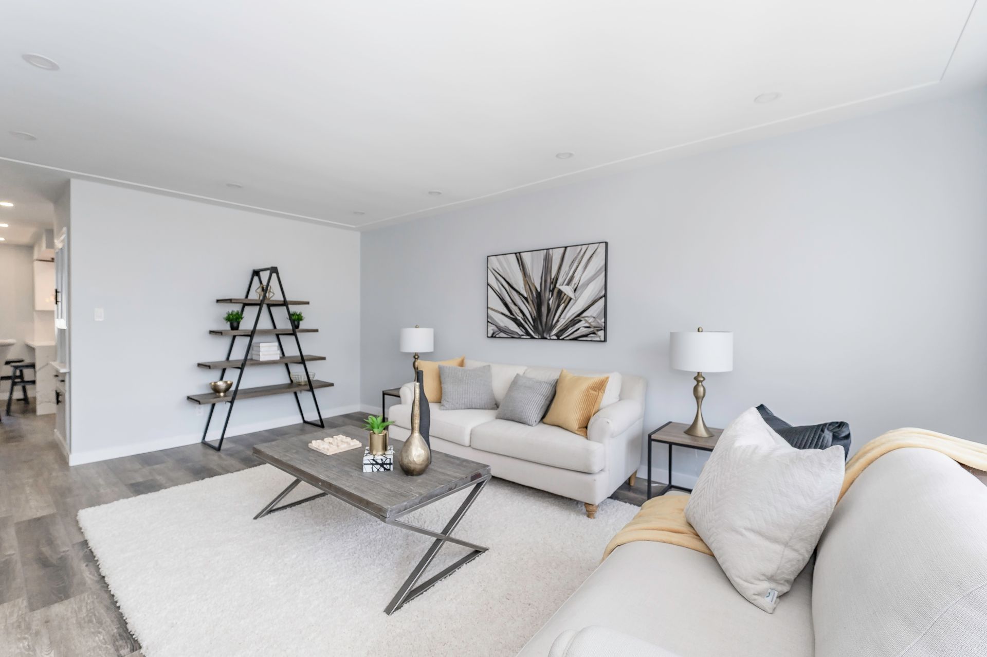 Living room with white sofa, rug, and light gray walls; includes shelves and a coffee table.