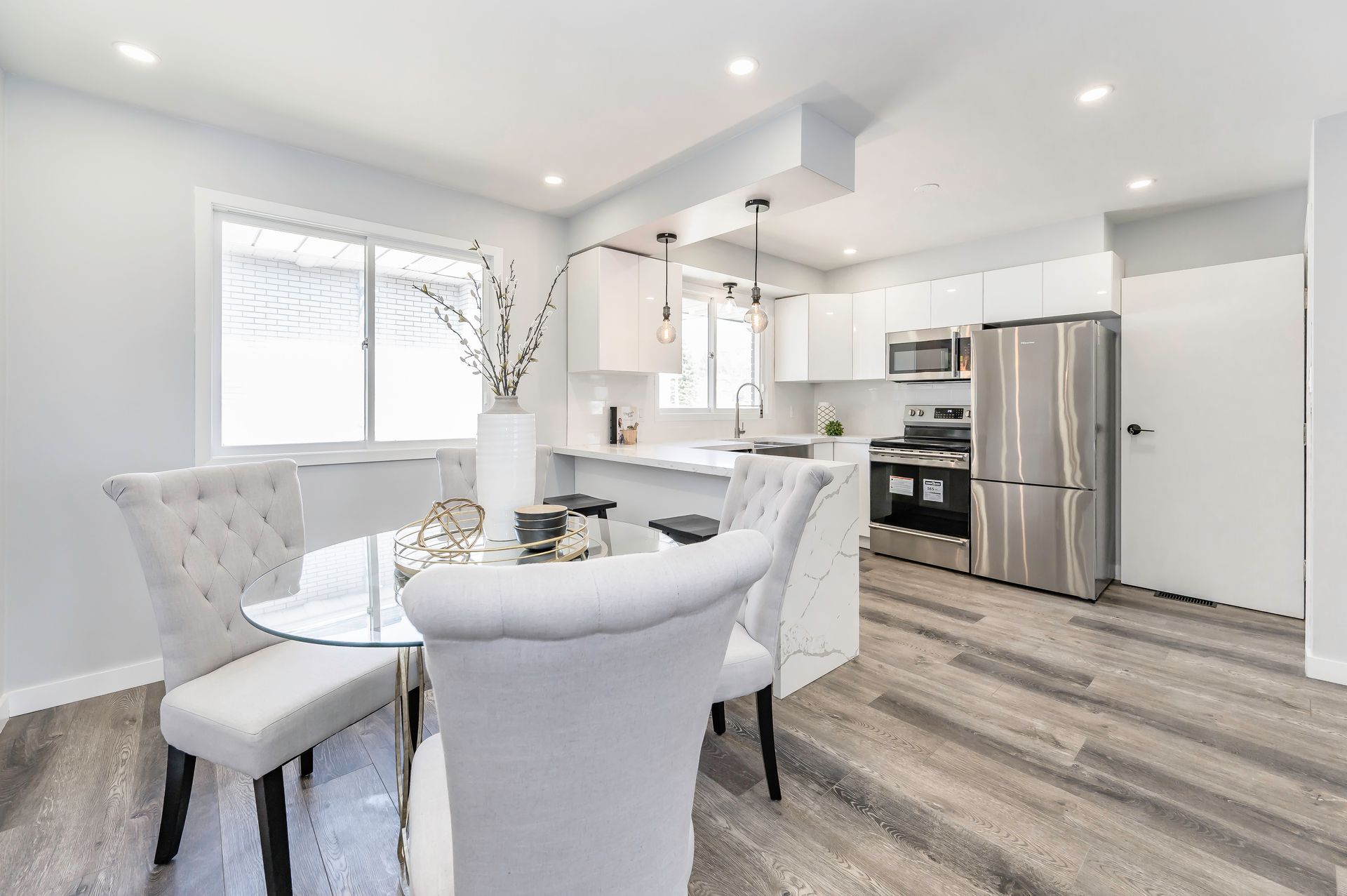 Modern kitchen with white cabinets, stainless steel appliances, and a glass dining table.