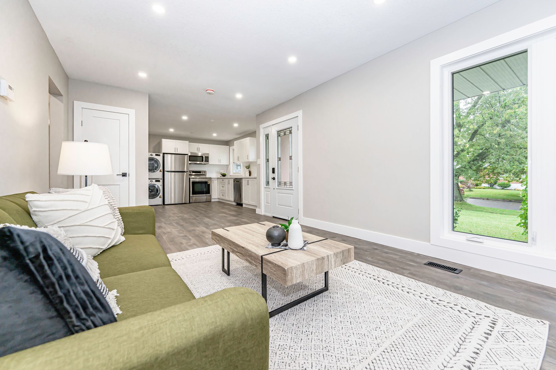 Green sofa in a bright living room with a view of green trees.