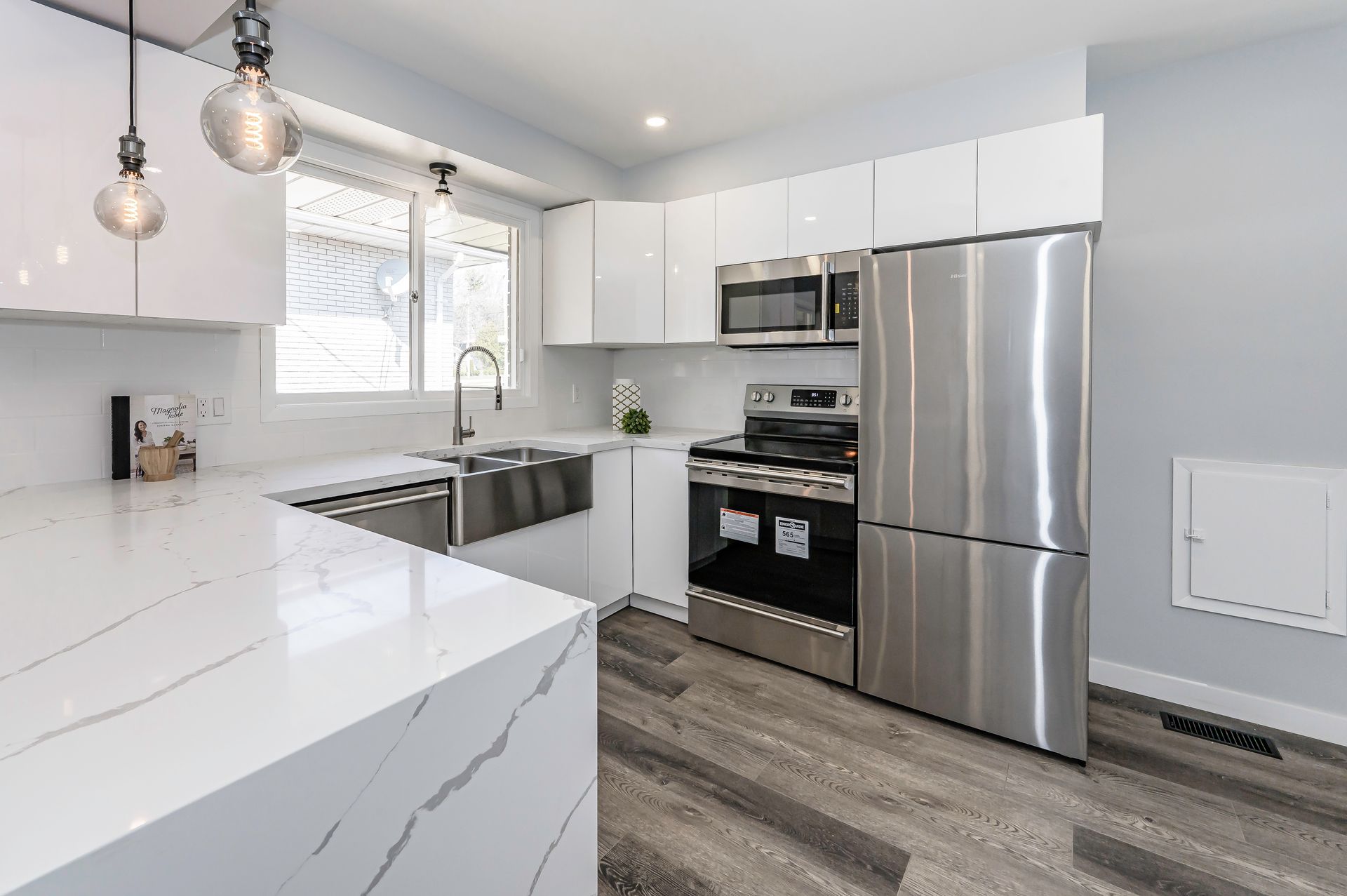 Modern kitchen with white cabinets, stainless steel appliances, and quartz countertops.