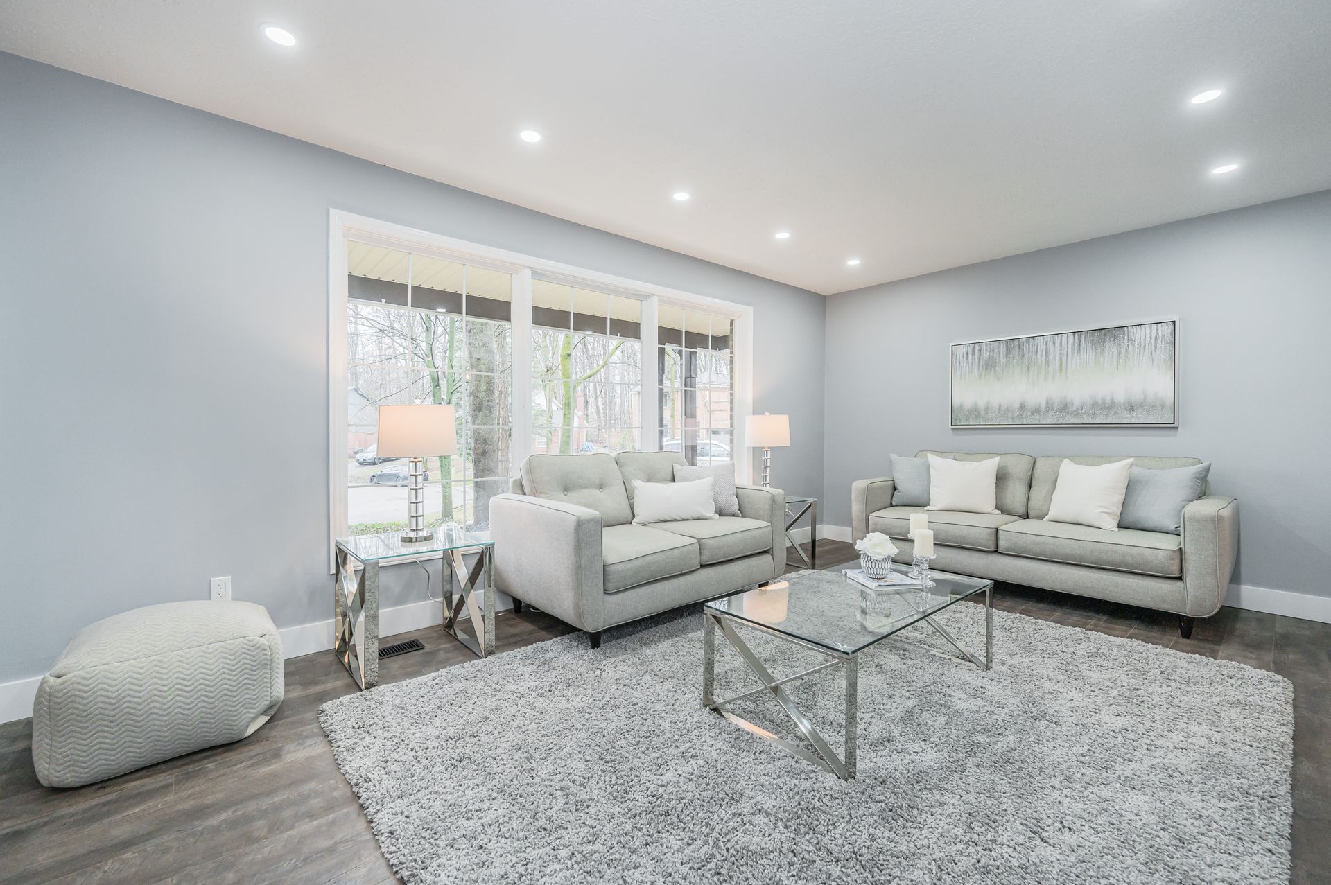Gray living room with two couches, a rug, and a glass coffee table.