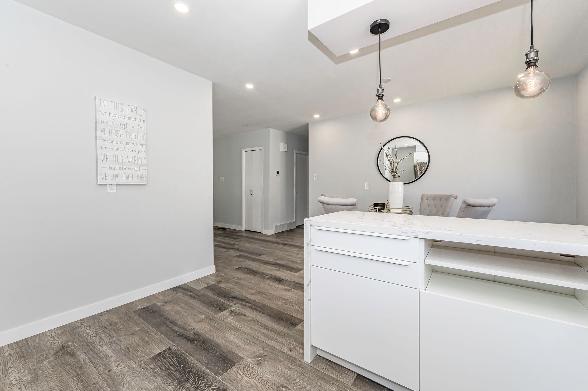 Modern, minimalist reception area with white desk, gray walls, and wood-look flooring.
