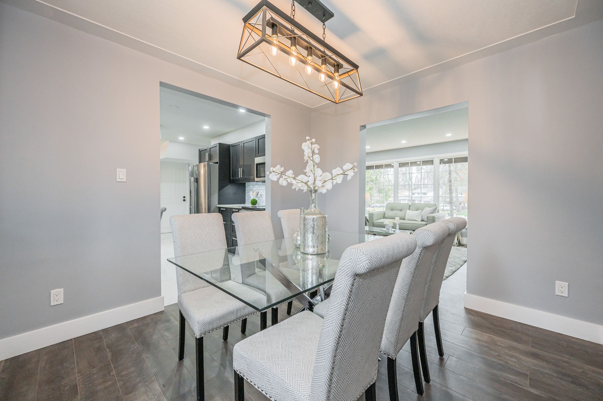 Dining room with glass table, patterned chairs, and a decorative light fixture.