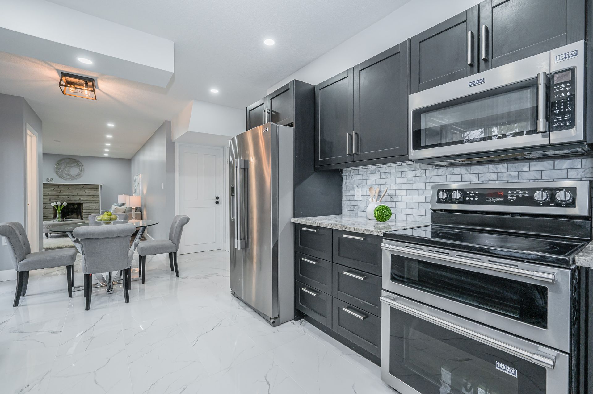 Modern kitchen with gray cabinets, stainless steel appliances, and a dining area.