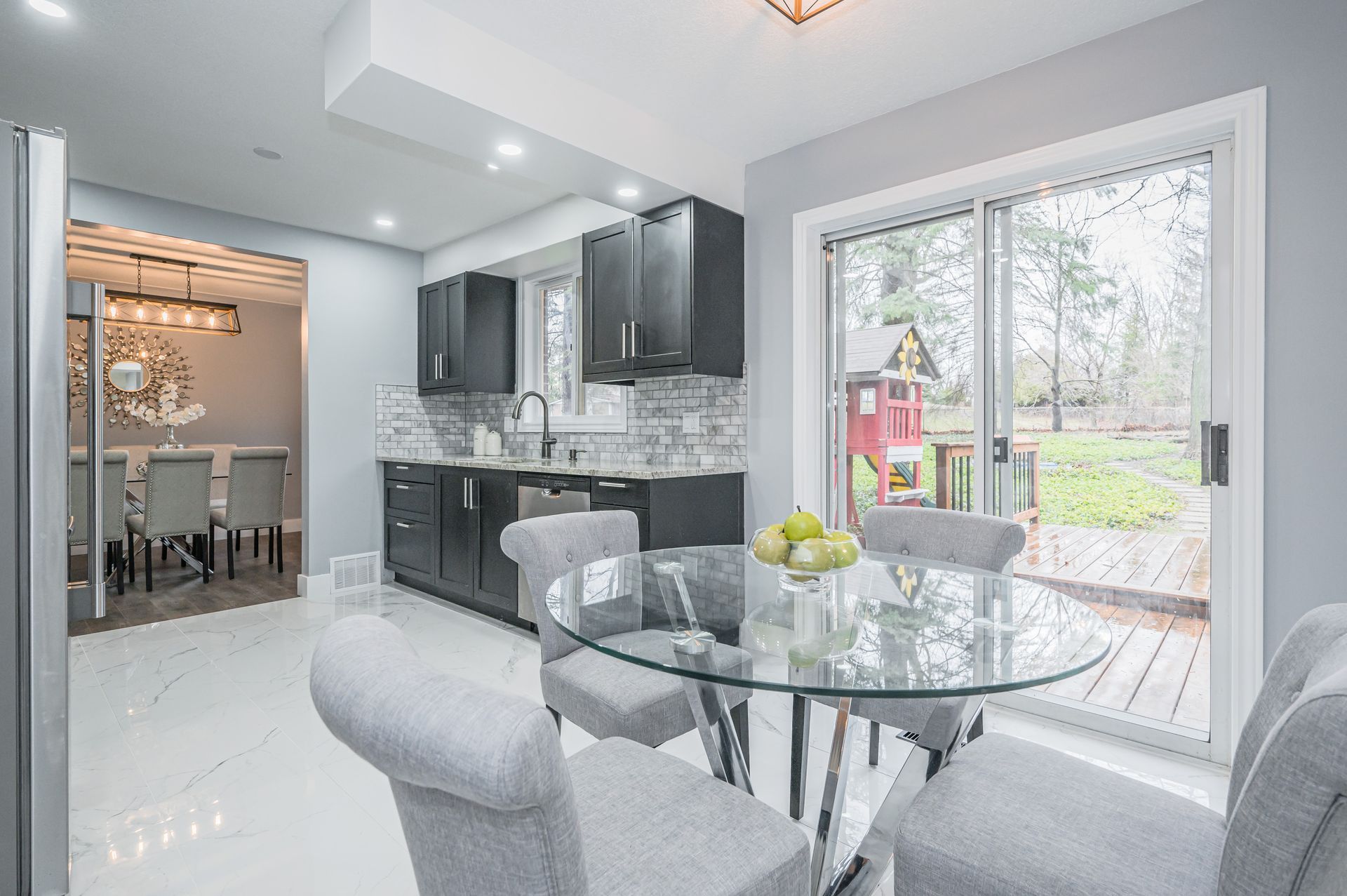 Kitchen with dark cabinets, glass table, and sliding door to backyard.