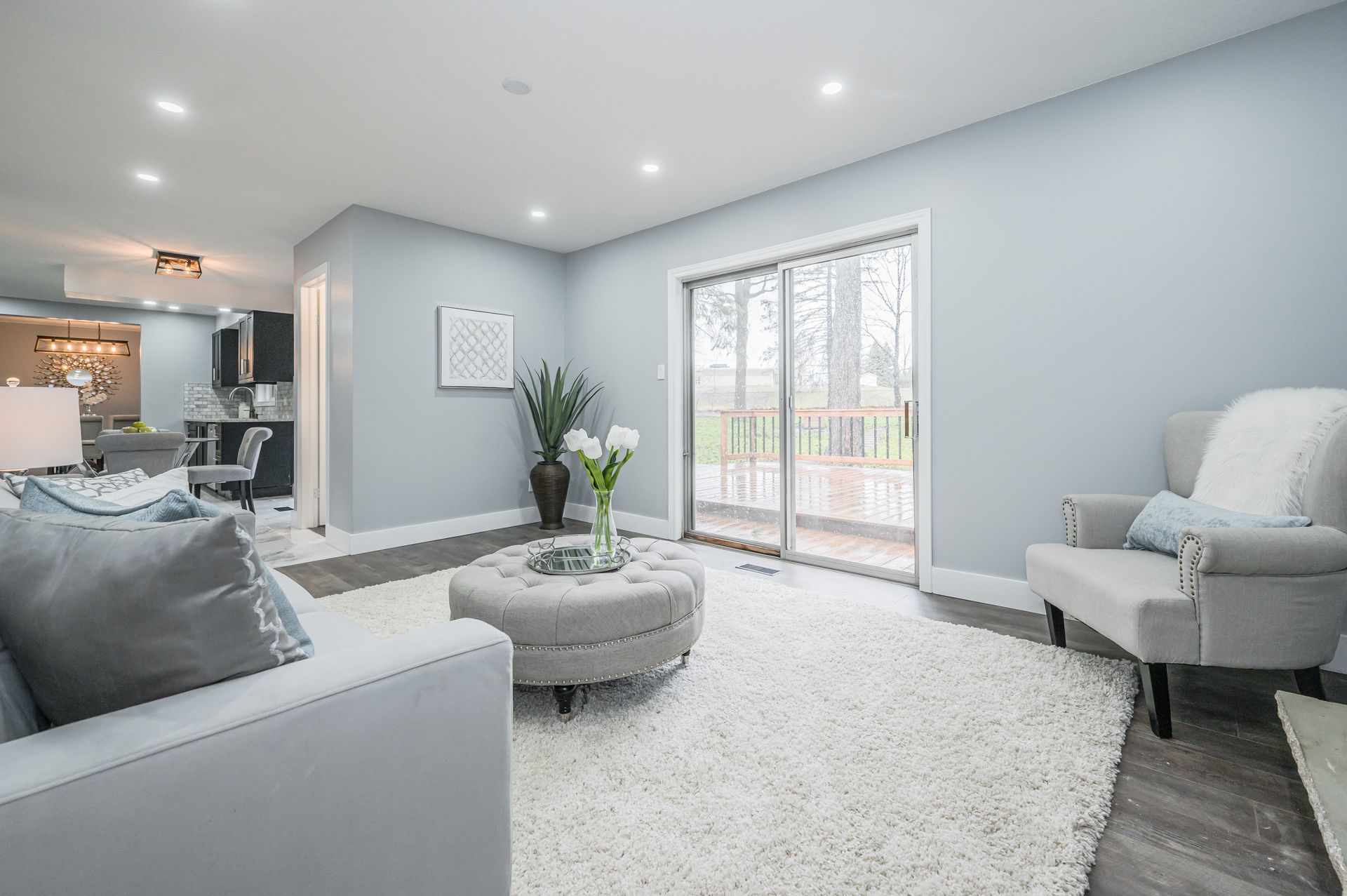 Living room with gray walls, white rug, and sliding glass door to a deck.