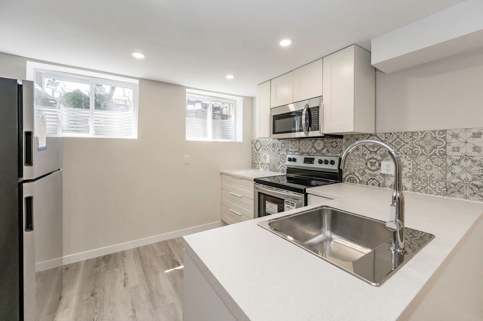Modern kitchen with white cabinets, stainless steel appliances, and patterned backsplash.