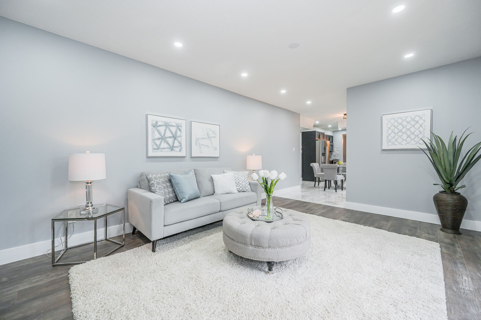 Modern living room with light gray walls, a fluffy white rug, and gray sofa.
