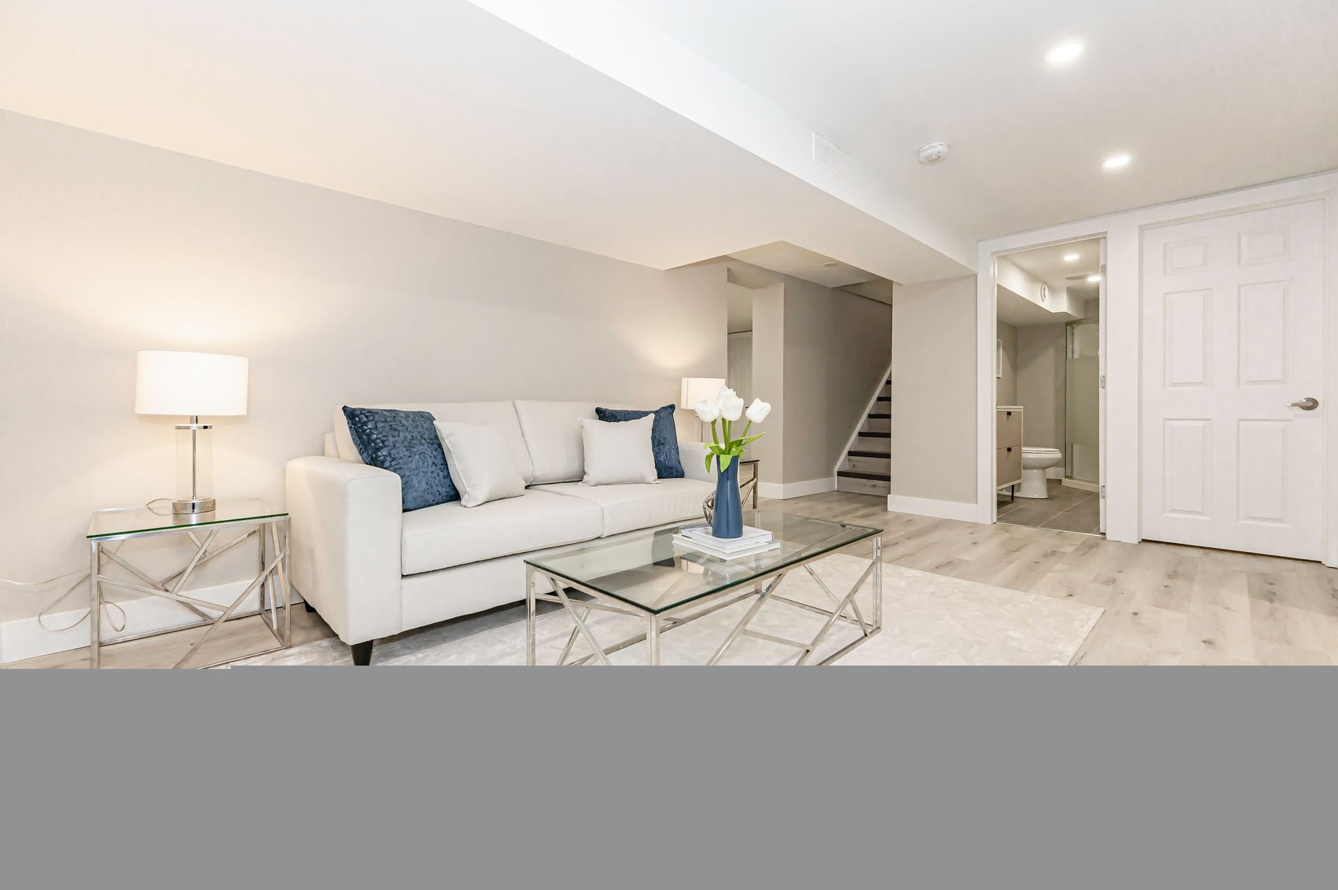 Living room with a white couch, glass coffee table, and light wood flooring.