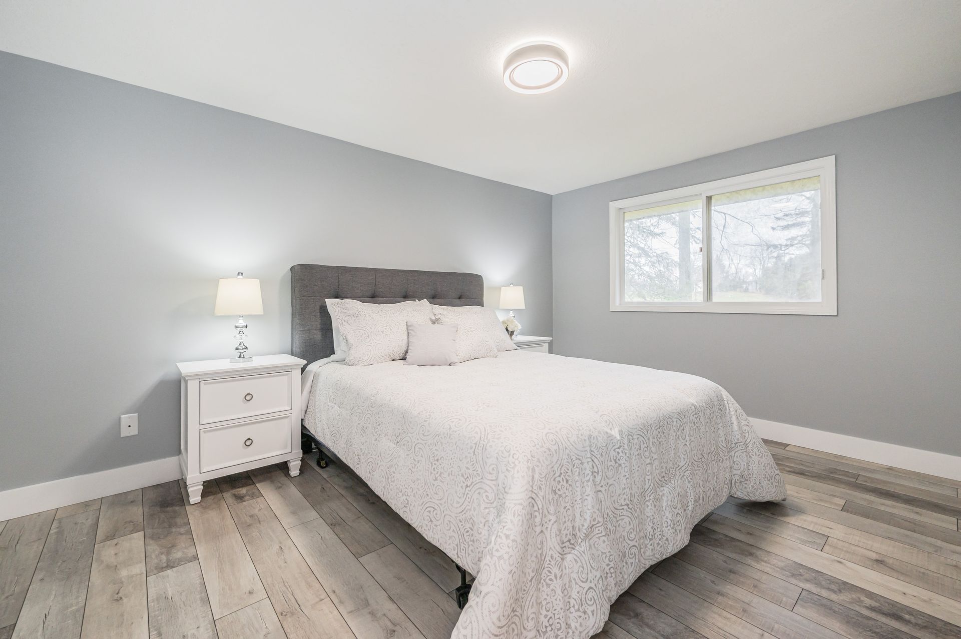 Bedroom with gray walls, white bedding, nightstands, and a window.