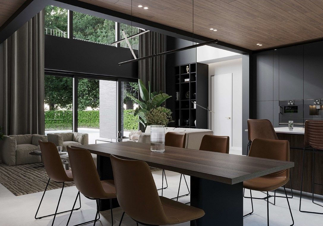 Modern dining room with a long table, brown chairs, and a dark kitchen. Large windows.
