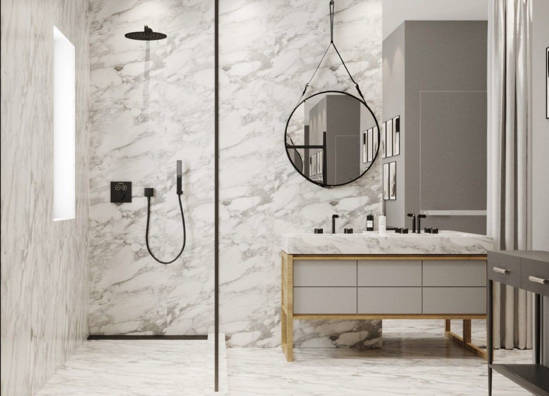 Modern bathroom with marble walls, glass shower, grey vanity, and round mirror.
