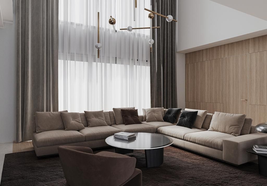 Spacious living room with tan sectional sofa, brown rug, and tall windows with sheer and solid curtains.