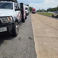 A row of tow trucks are parked on the side of the road.