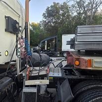 A semi truck with a trailer attached to it is parked in a parking lot.