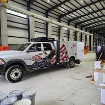 A truck with an american flag painted on the side is parked in a warehouse.