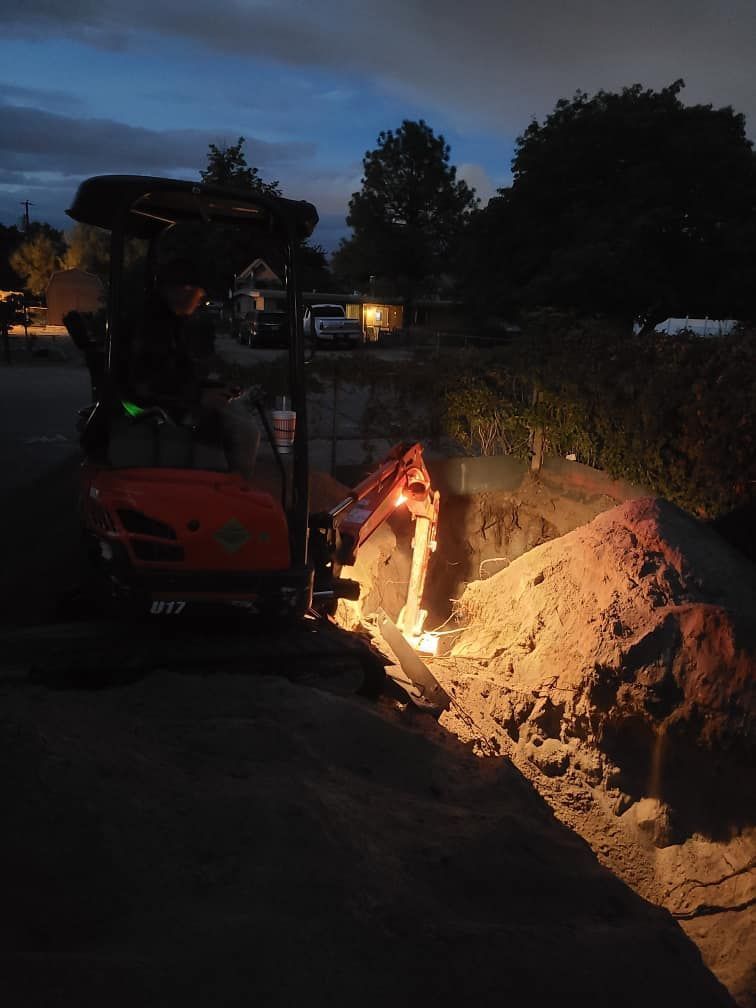 A tractor is digging a hole in the ground at night.