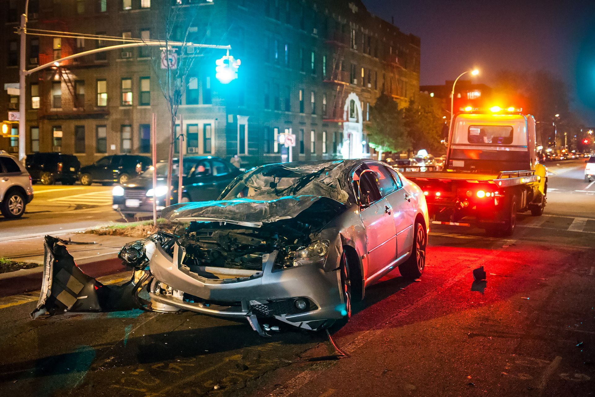 A car accident on a city street at night with a tow truck in the background.