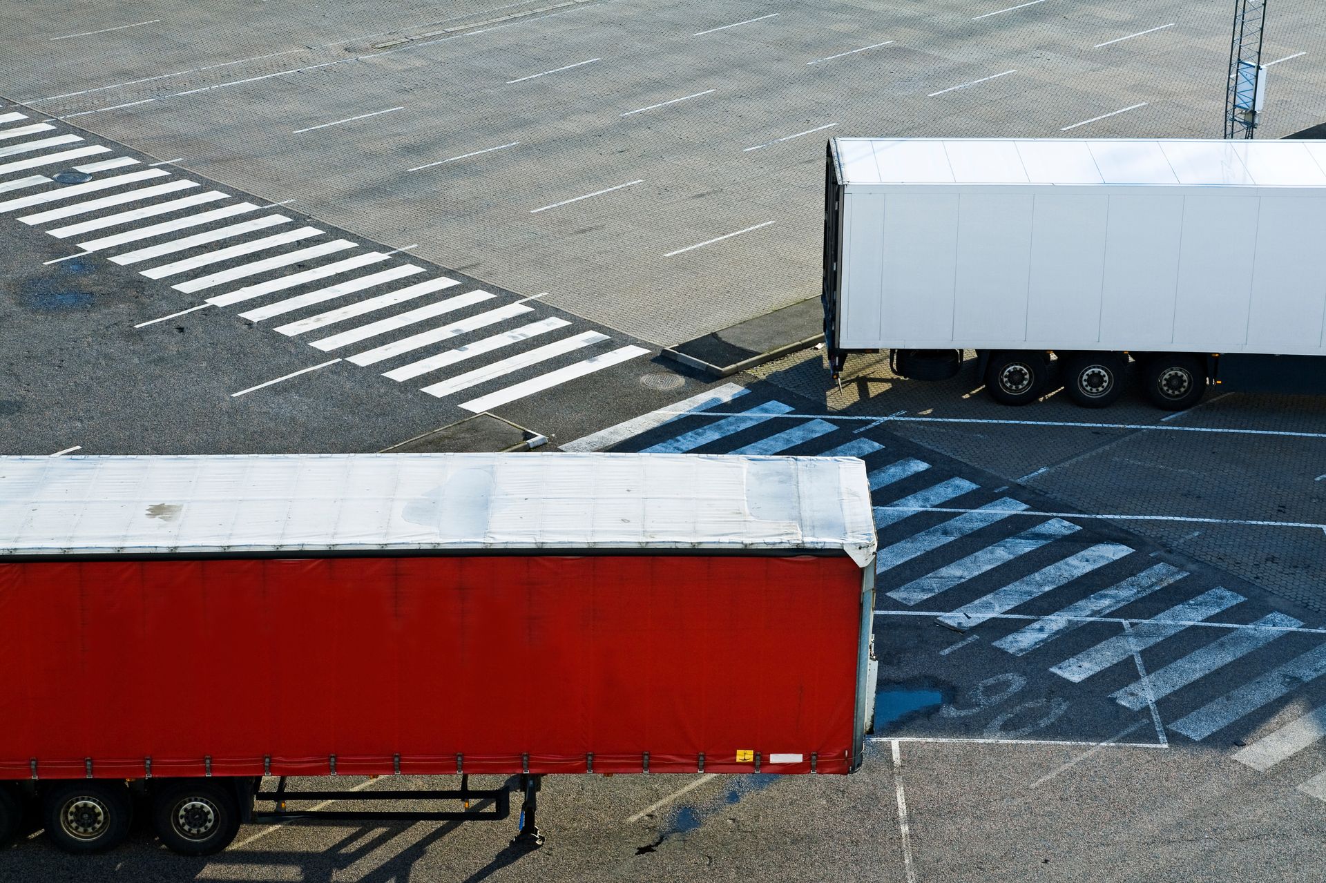 Two semi trucks are parked next to each other in a parking lot.