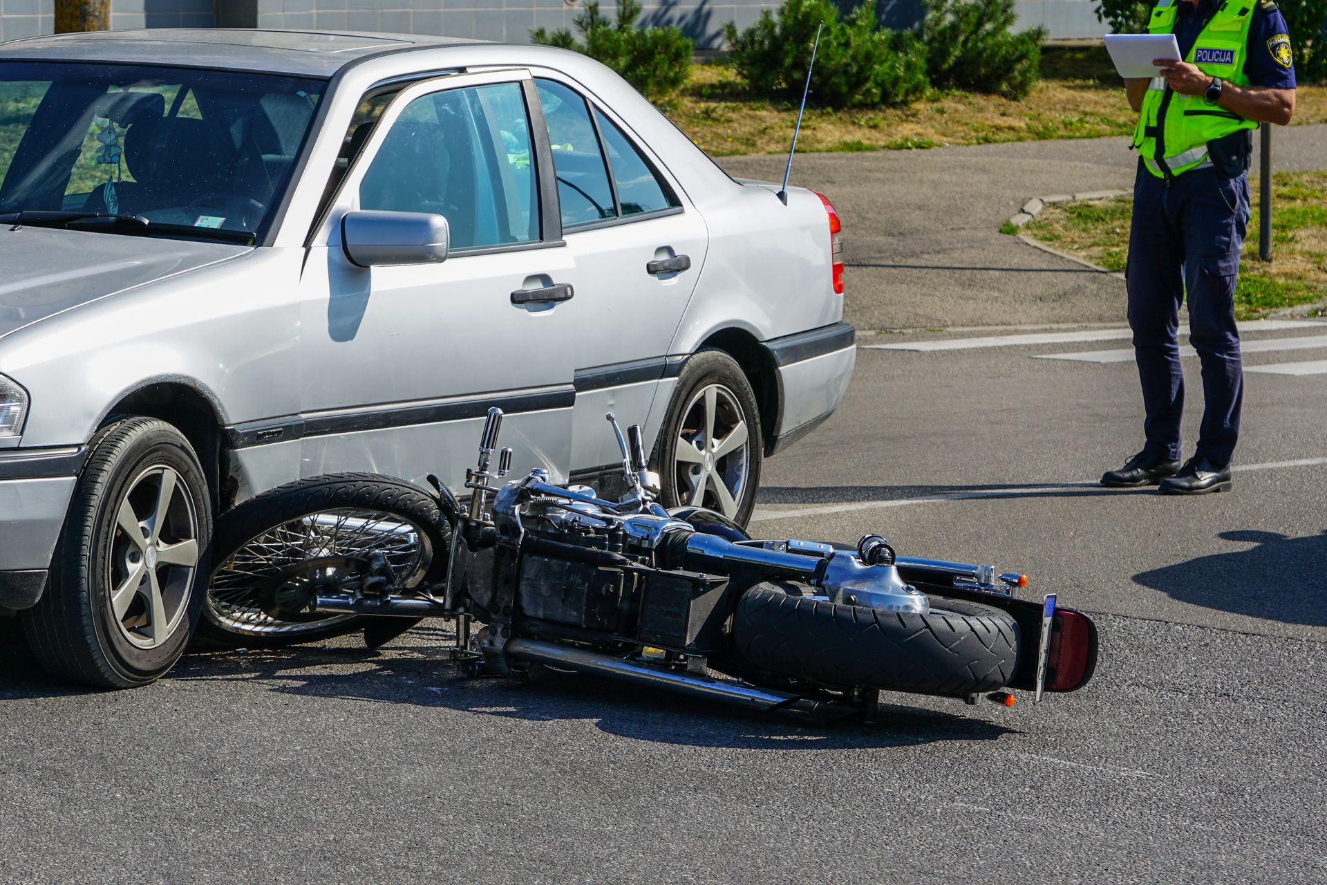 A motorcycle is laying on the ground next to a silver car.