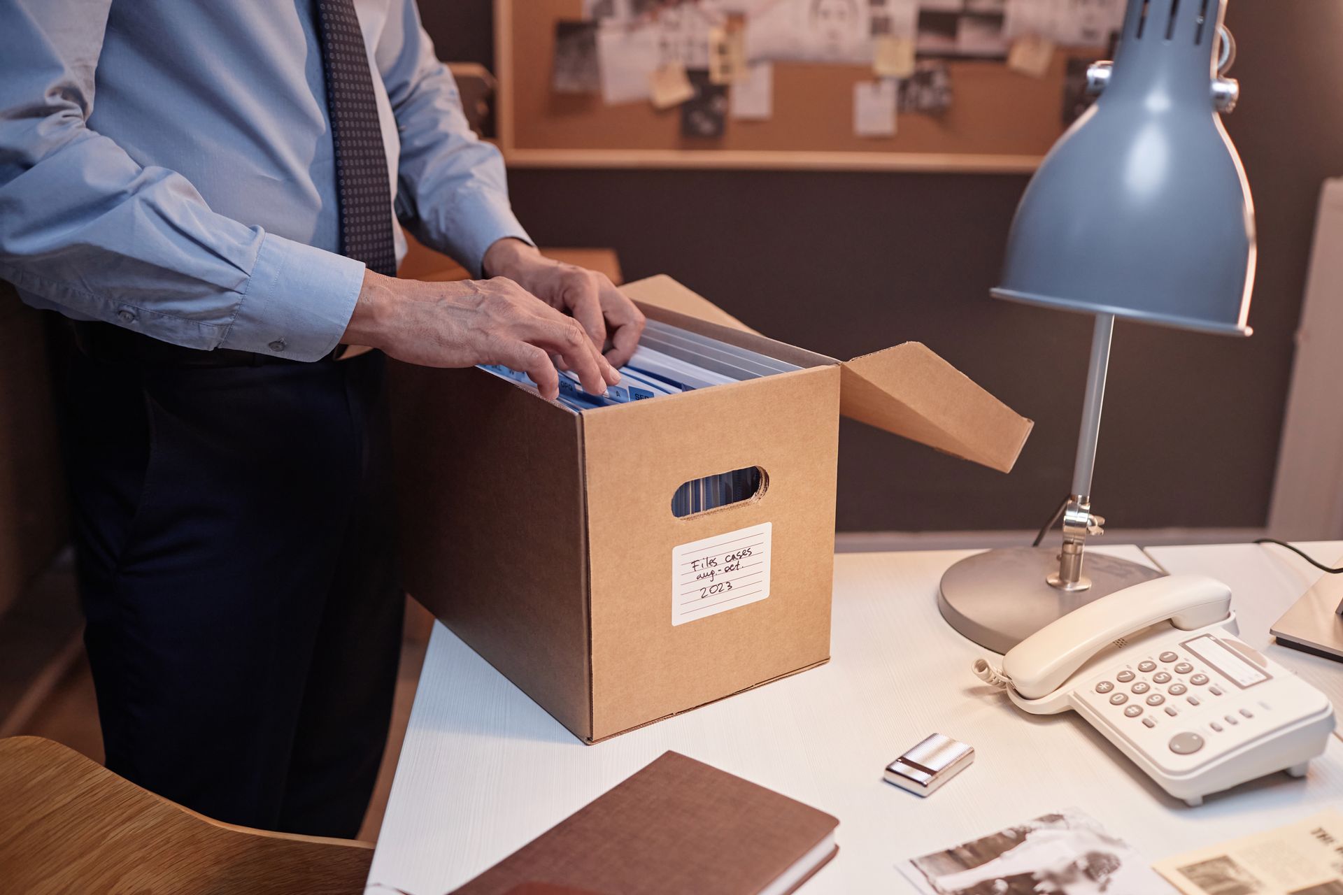 Un uomo apre una scatola di cartone piena di documenti.