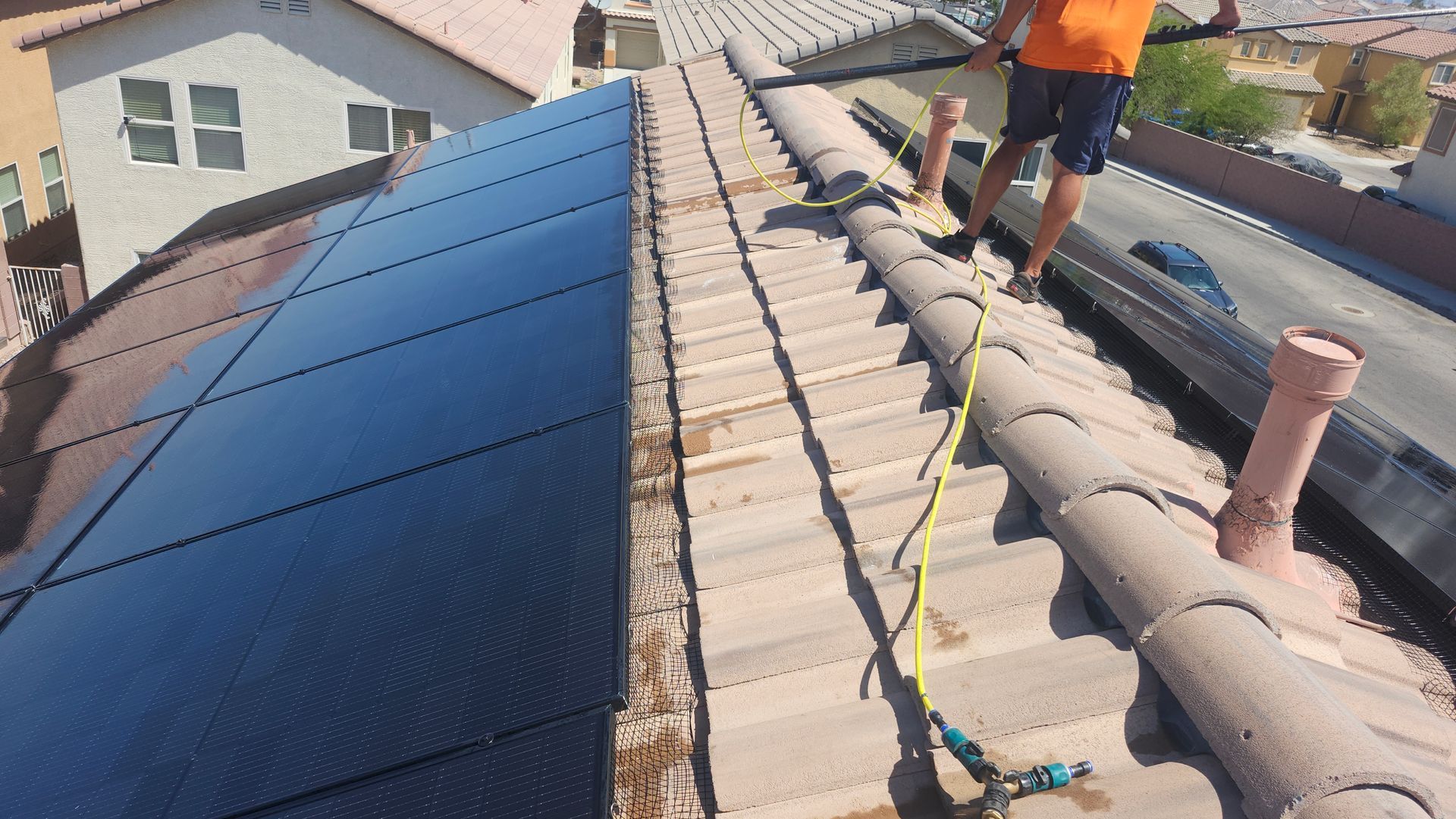 Cleaning solar panels with installed pigeon-proofing mesh on residential Las Vegas rooftops