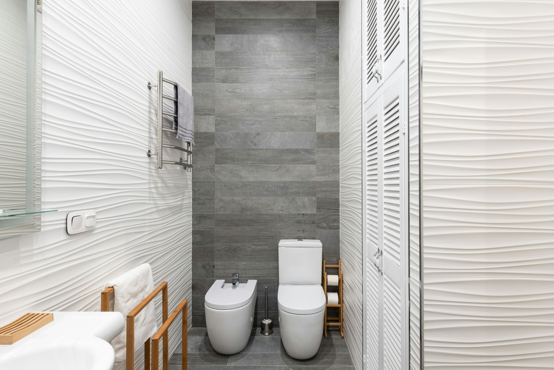 A bathroom with two toilets , a bidet and a sink.