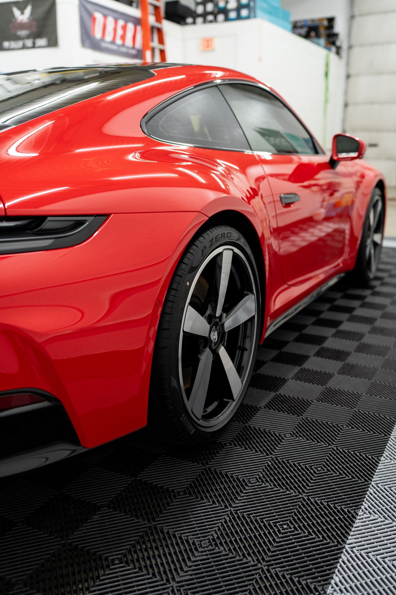 Red Porsche sports car parked on a checkered floor in a garage.
