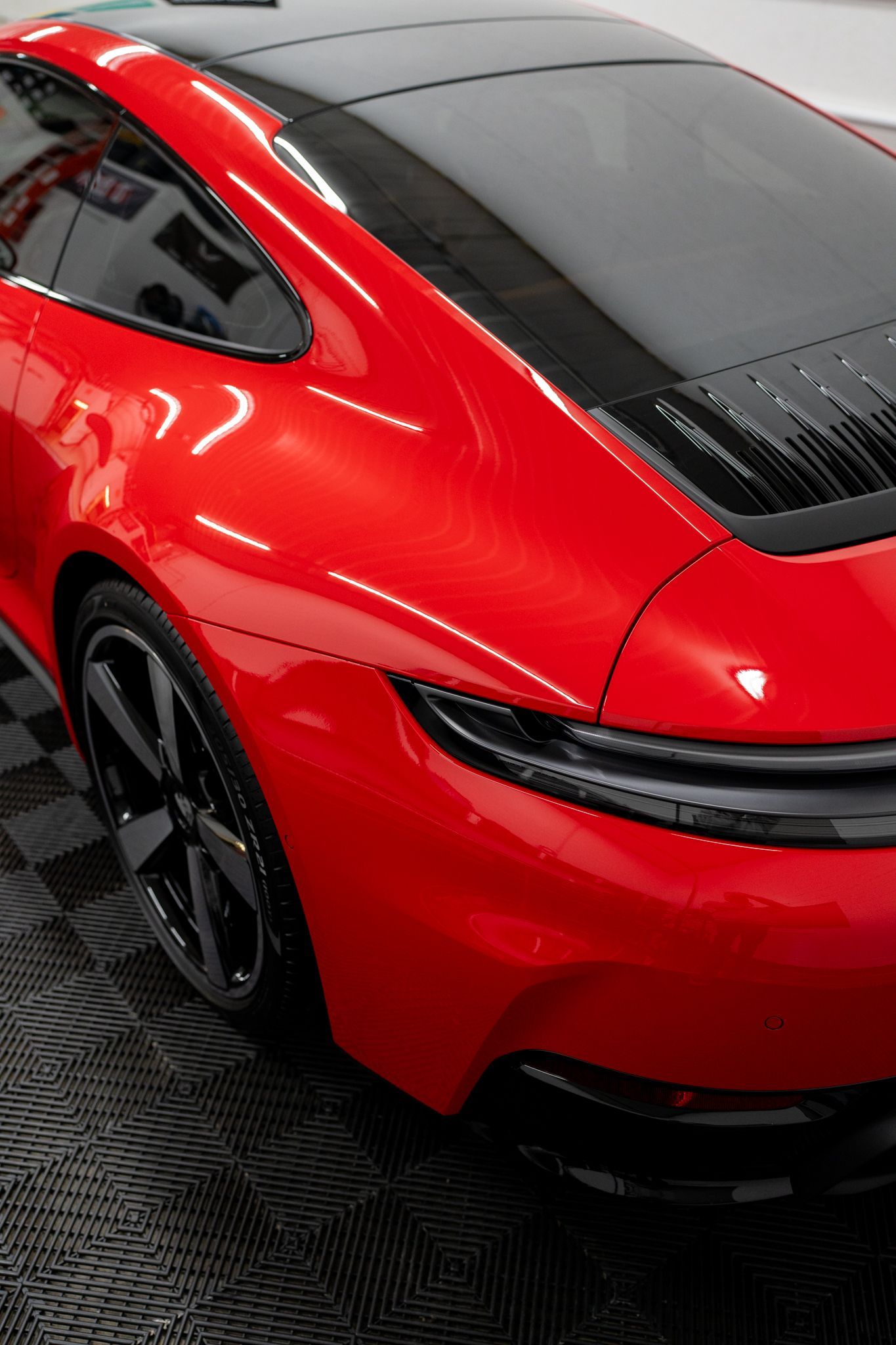 Red Porsche sports car with black roof, parked indoors.