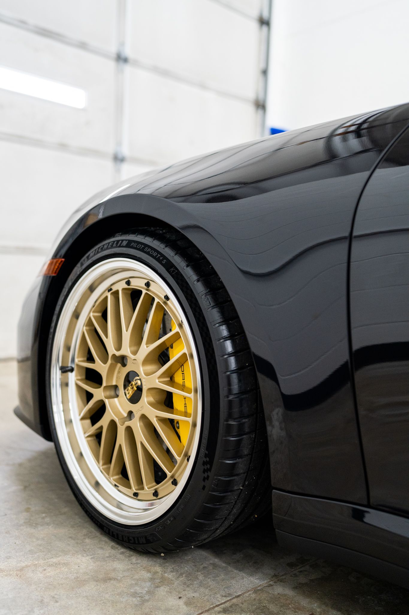 Black car with gold rims and yellow brake calipers.