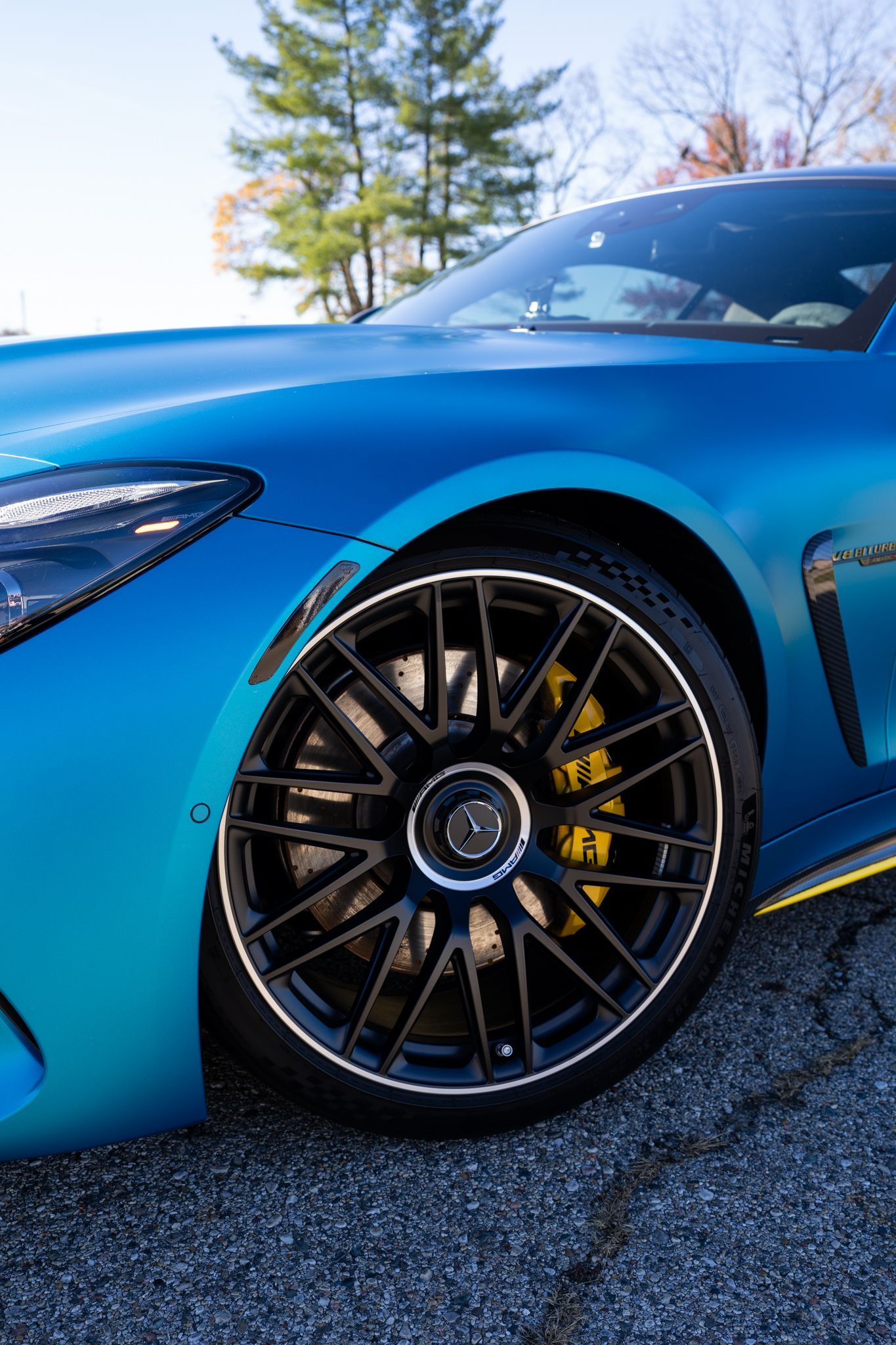 Blue sports car wheel, black rim, yellow brake caliper.