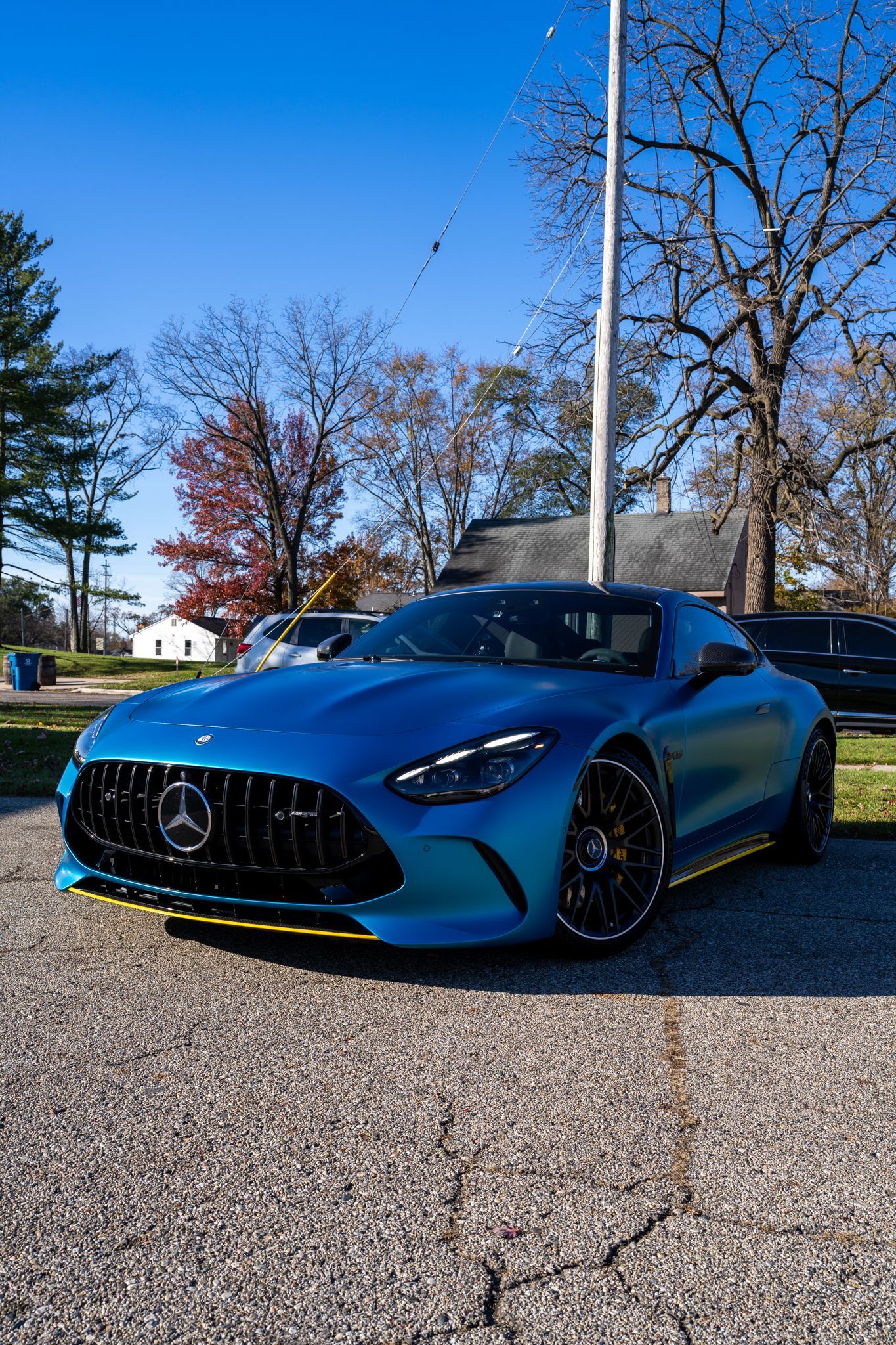 Blue Mercedes-AMG GT sports car parked on asphalt with a sunny outdoor background.