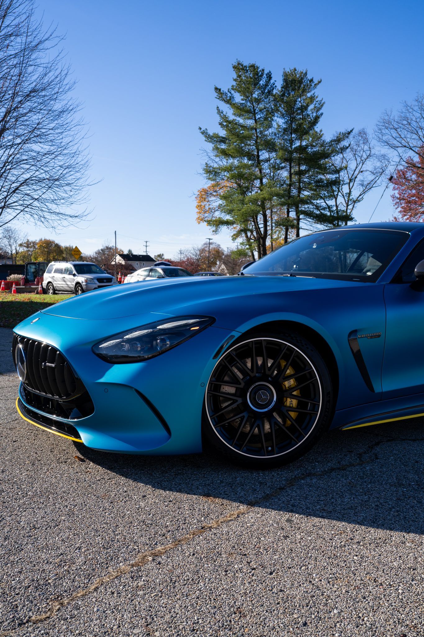 Blue sports car parked on gravel, sunny day.