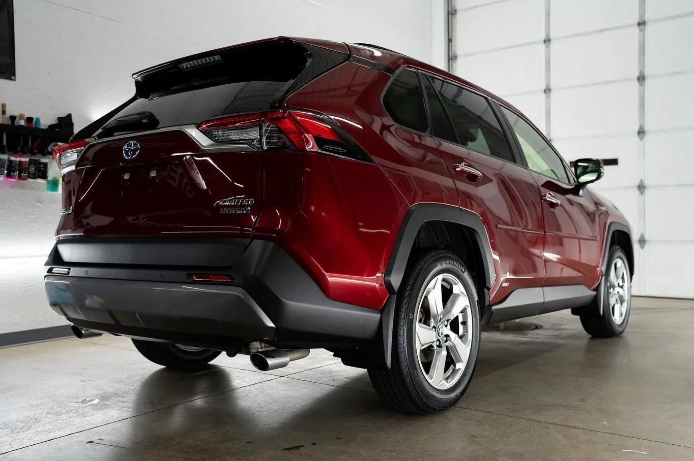 A red toyota rav4 is parked in front of a garage door.