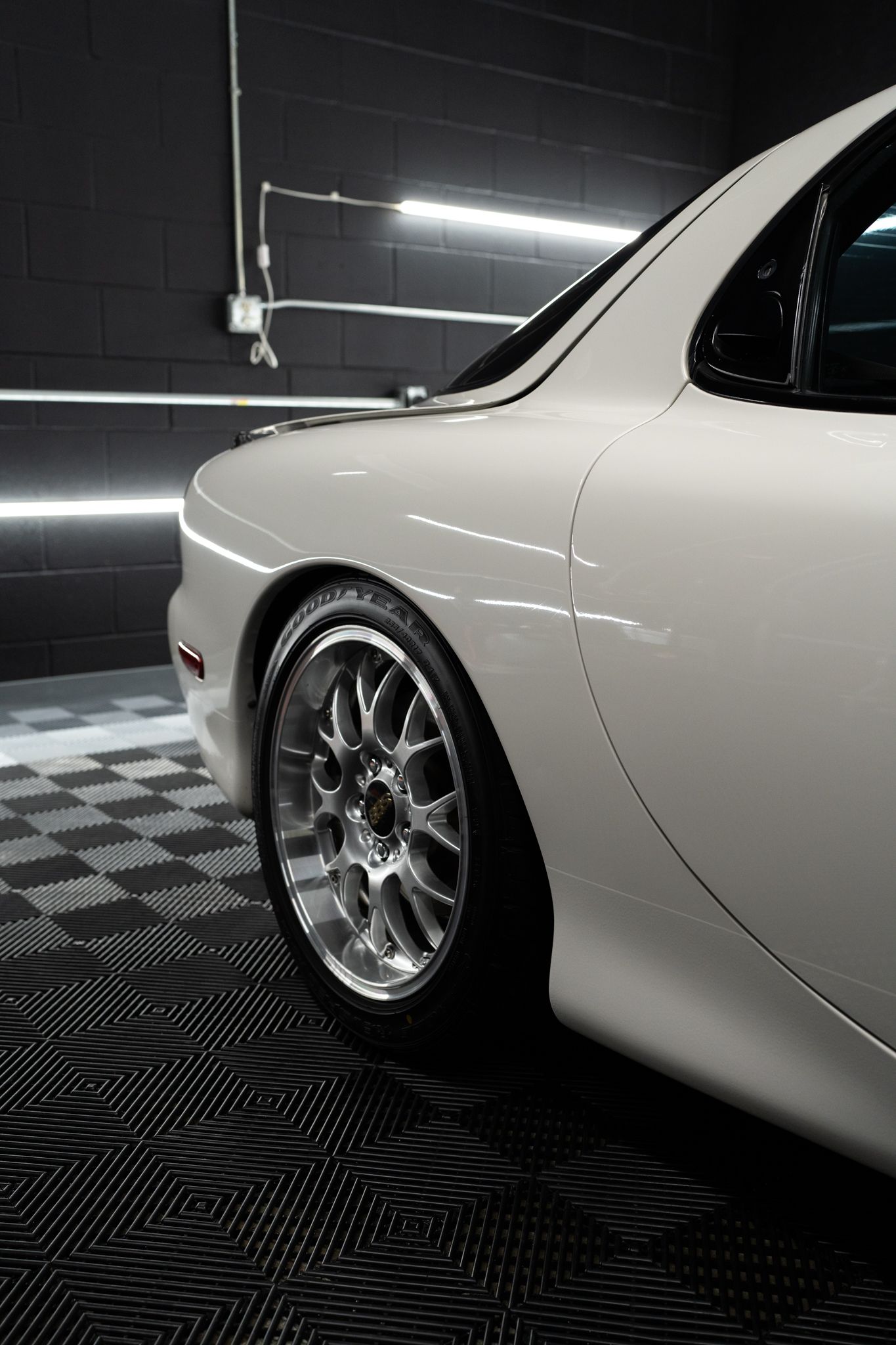 A white sports car is parked in a garage.