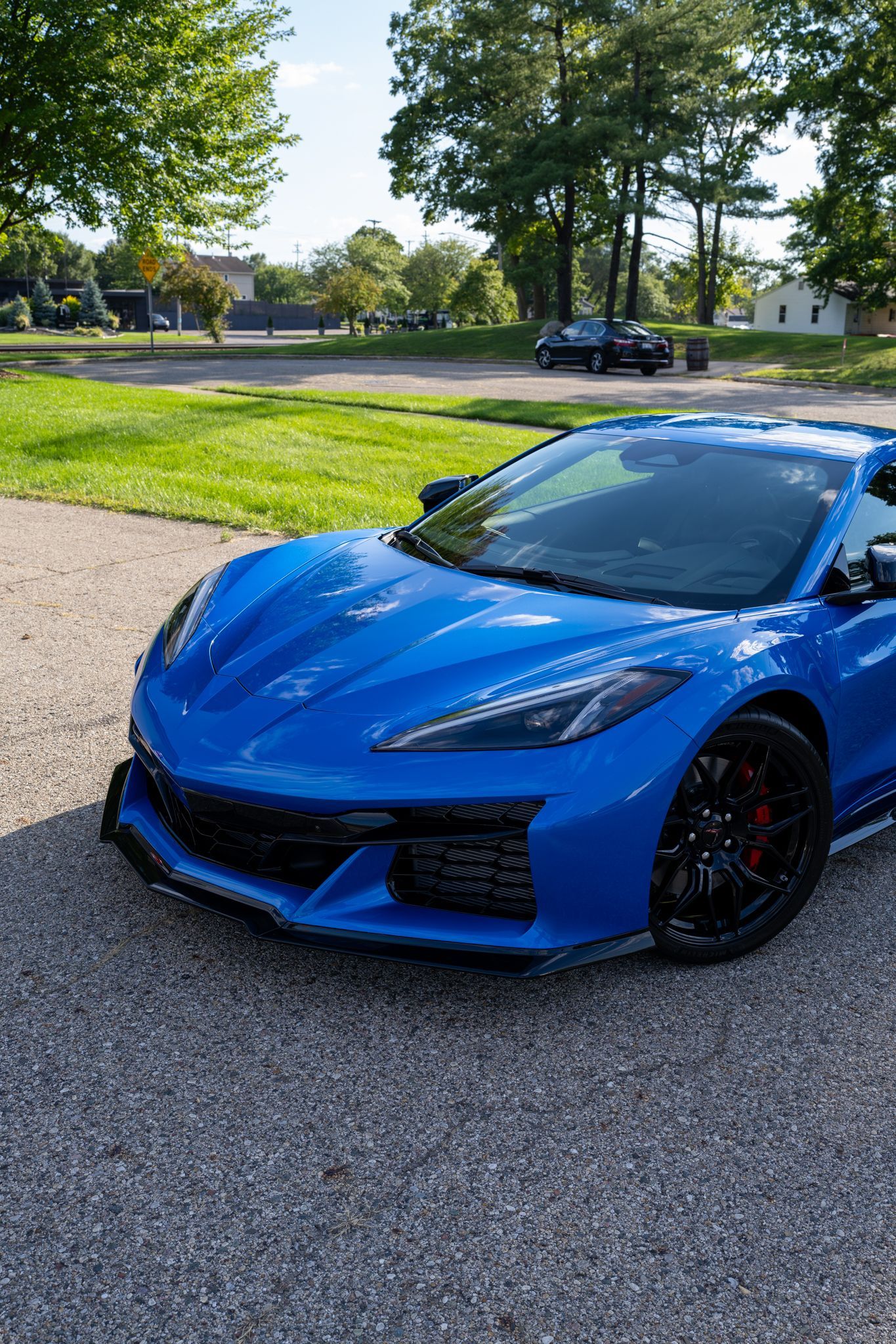 Blue sports car parked on gravel driveway.