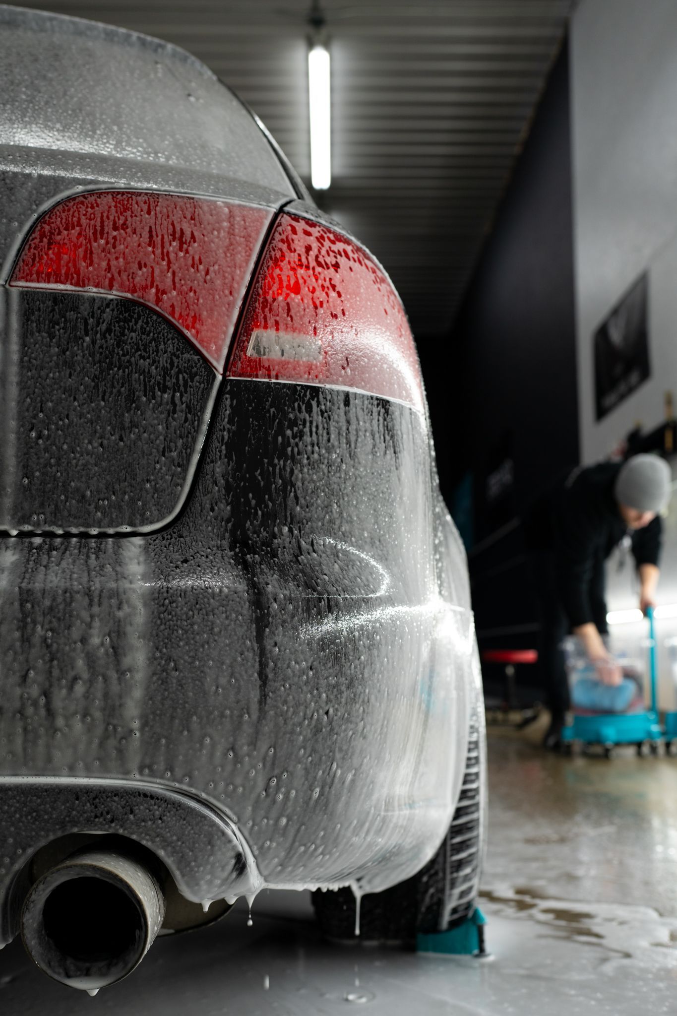 A man is washing a dirty car in a garage.