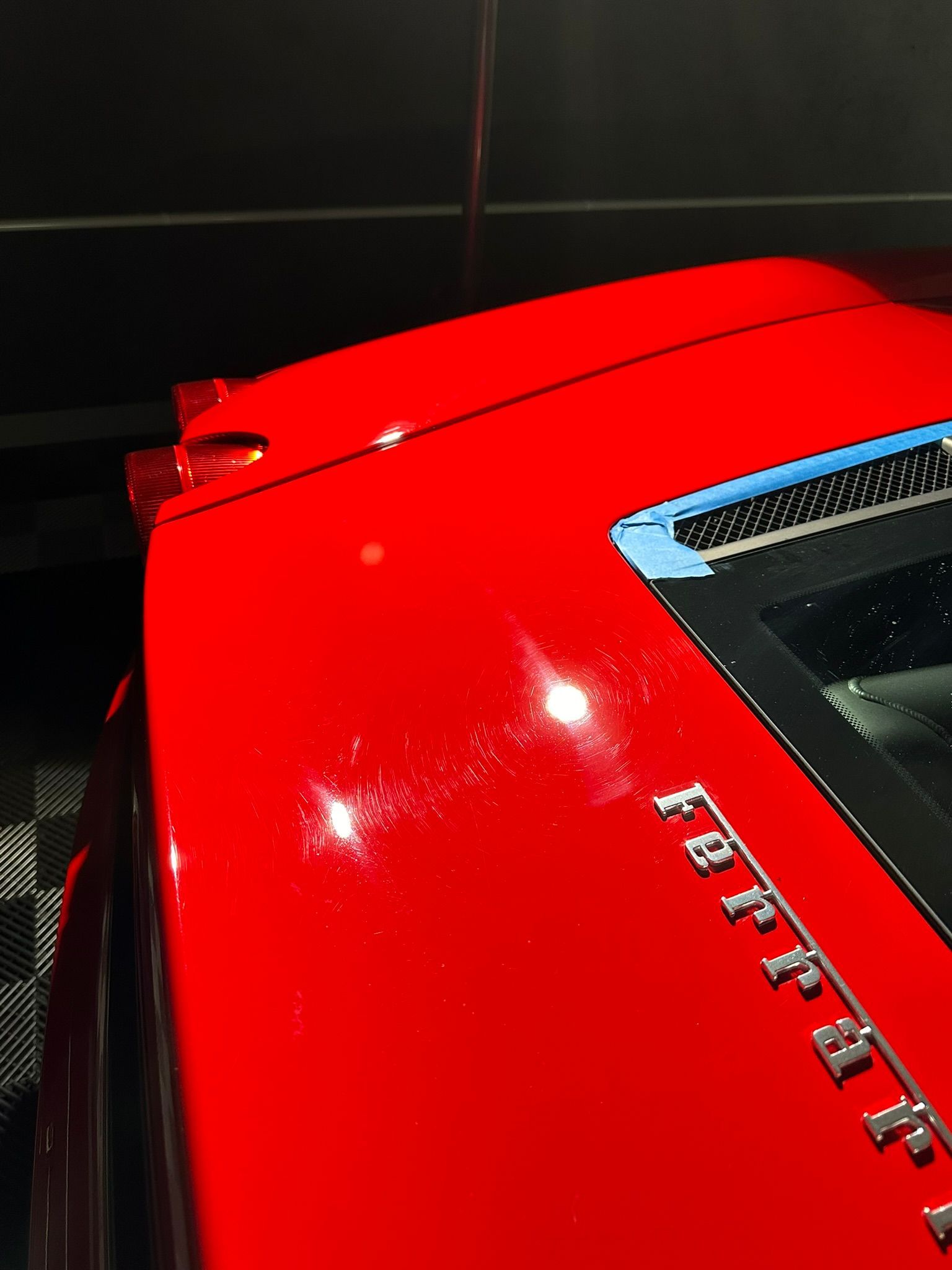 A red ferrari car is parked in a dark room
