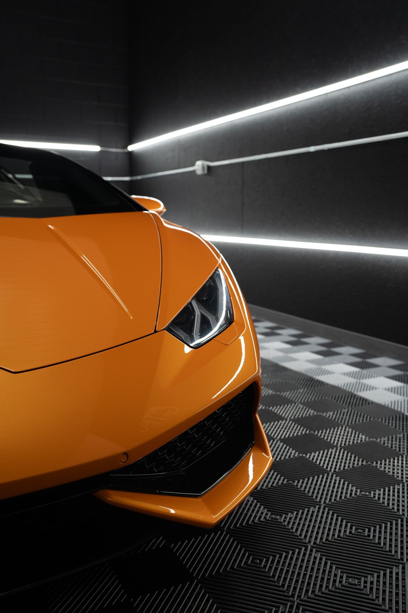An orange lamborghini huracan is parked in a garage.