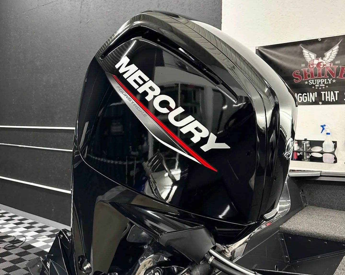 A black mercury outboard motor is sitting on a checkered floor