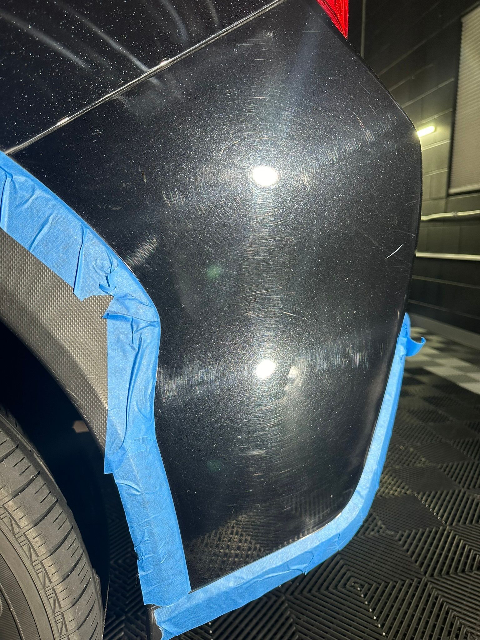 A close up of a black car with blue tape on it.