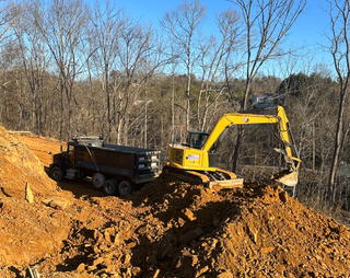 A yellow excavator is loading dirt into a dump truck.