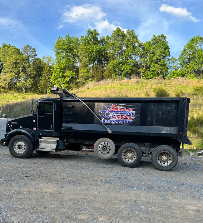 A black dump truck is parked in a gravel lot.