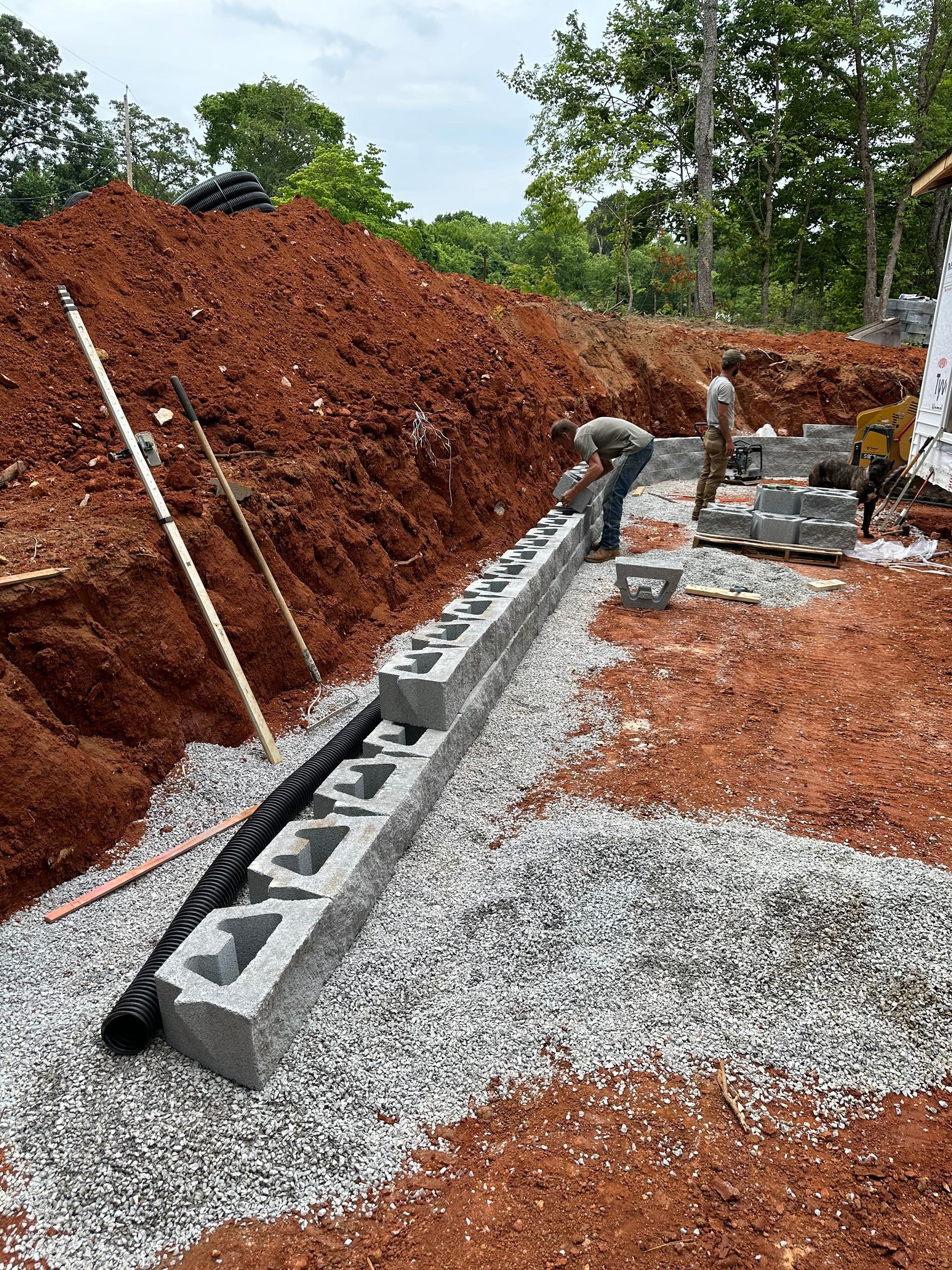 A man is working on a concrete wall in a dirt field.