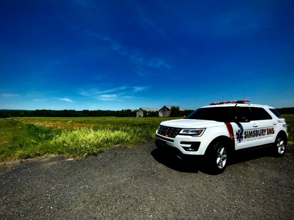 A white EMS flycar is parked on the side of the road.