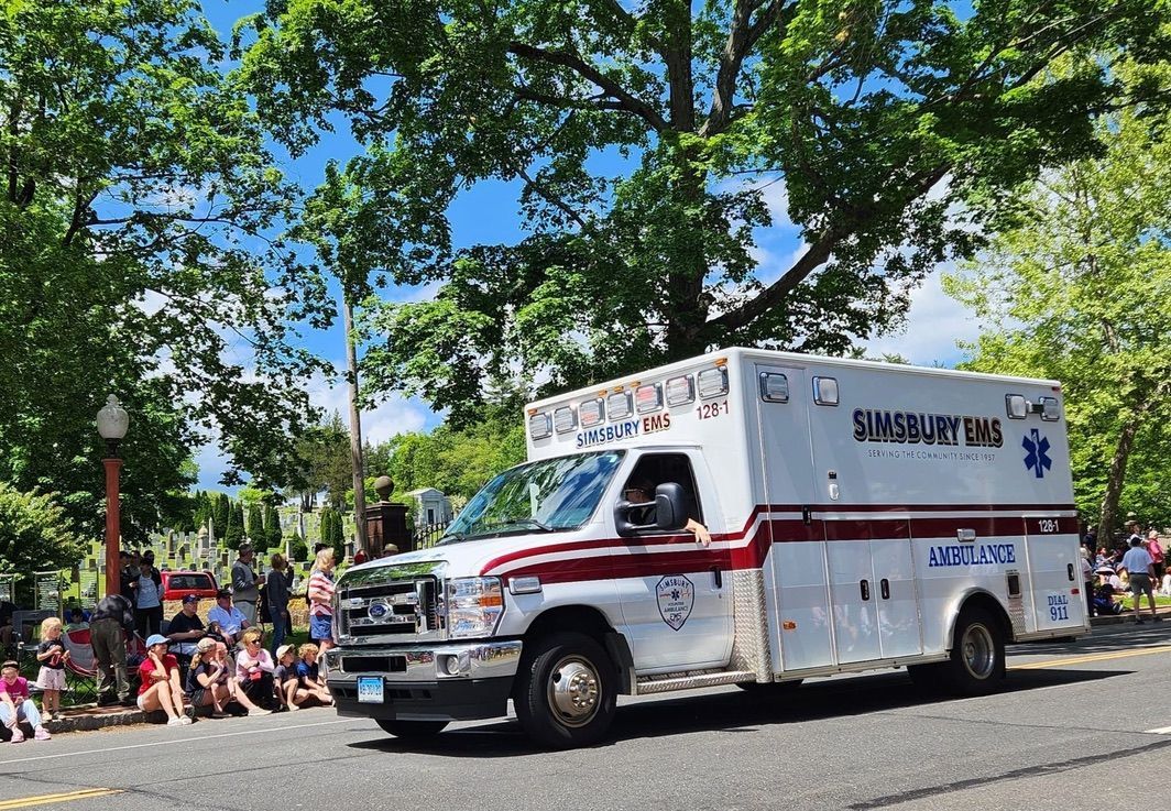 A Simsbury ambulance is driving down a street in a parade.