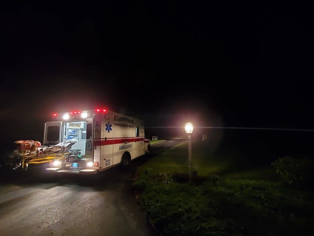 An ambulance is parked on the side of the road at night.