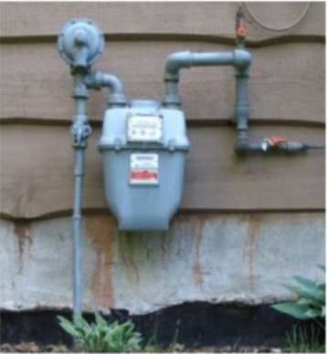 A gas meter is attached to the side of a house