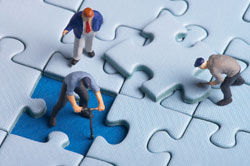 A group of miniature people are working on a puzzle